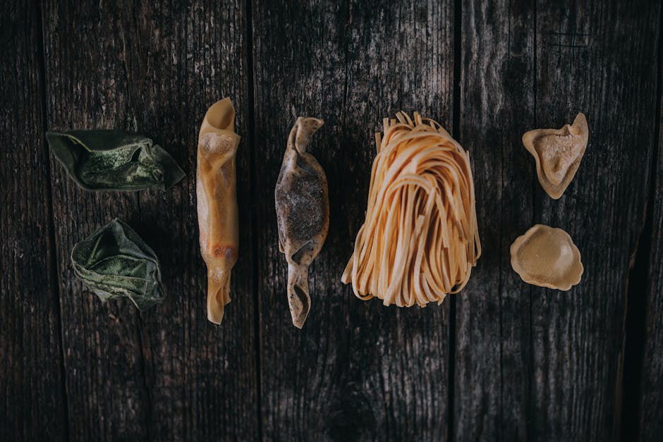 Top view of various Italian pasta on rustic wood surface, showcasing a variety of textures and shapes.
