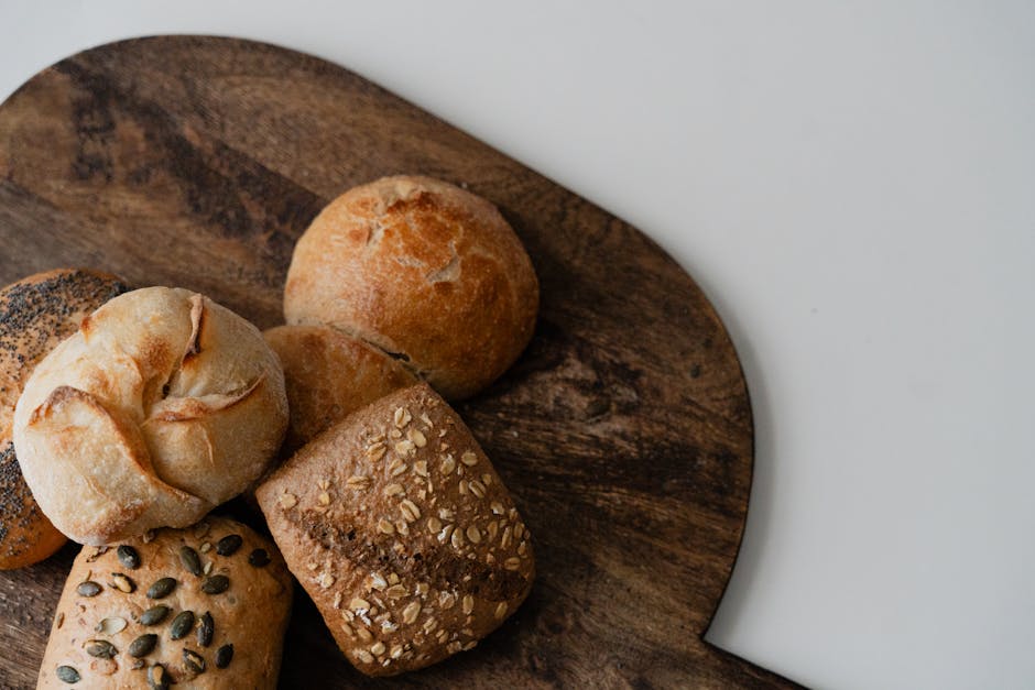 A variety of artisan bread rolls arranged on a rustic wooden board, perfect for food displays.